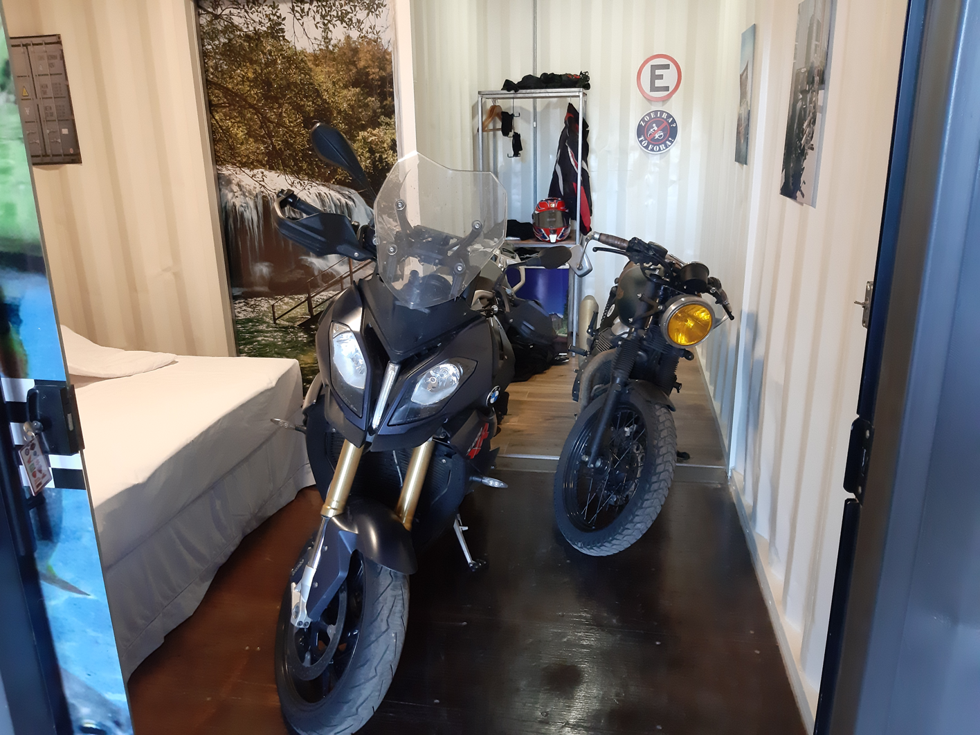 Moto estacionada dentro do apartamento MotoBox ao lado da cama